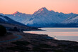 © James Fulton/Stocksy - Pink light on snow covered mountains and glacial lake at sunset