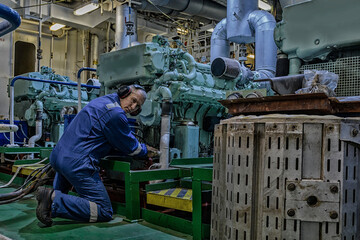 Wall Mural - Marine Engineer in blue overall working in Engine room of ship. Work at sea. Motorman.