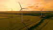 AERIAL, SILHOUETTE: Golden glowing morning sky above a wind farm in countryside