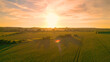 AERIAL, LENS FLARE: Vast and lush wheat fields in beautiful golden evening light