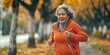 Female senior citizen jogging in the park with headphones listening to music and podcasts