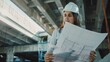 Female engineer reviewing blueprints at industrial site.