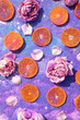 Sliced orange and flowers with glitter and sequins. Summer aesthetic visual concept. Blue, purple and pink glitters with sparkle.