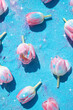 Tulip flowers adorned with glitters and sequins sparkling on a blue background. Spring and Summer nature concept.