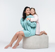 © New Africa - Beautiful mother hugging with little daughter on pouf against white background