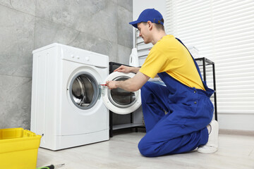 Wall Mural - Plumber repairing washing machine in bathroom, low angle view