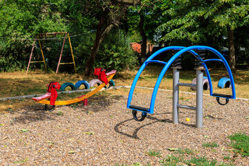 Sticker - A playground with a red and blue swing set and slide