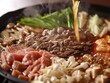 Close-up of sukiyaki preparation showcasing the glossy sheen of ingredients in a rich