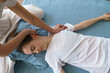 © Alex - young masseuse does a Thai massage on the floor massaging her neck and shoulders