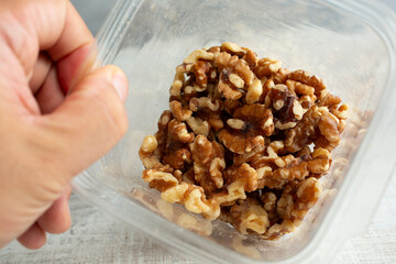 Sticker - A view looking into a plastic container of walnut pieces.