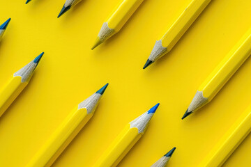 colorful array of pencils on bright yellow background with contrasting blue pencil in the center