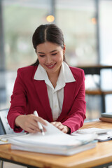 Wall Mural - Businesswoman working with online data on laptop and folders Stack of documents to analyze, plan, and calculate financial statistics, and taxes at a desk in a modern office.