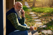Gray-bearded old man is relaxing on the veranda of country house