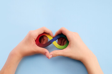 Wall Mural - Autistic boy hands and rainbow eight infinity symbol. Autism awareness day symbol.