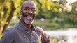 © Keitma - Black afro american man in his 50s who exudes happiness and a sense of feeling truly alive in a beautiful natural park near a lake, genuine smile on his face, relaxed and confident male who found joy