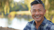 © Keitma - Asian american man in his 50s who exudes happiness and a sense of feeling truly alive in a beautiful natural park near lake, genuine smile on his face, relaxed and confident male who found joy