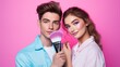 A young handsome makeup artist guy applies makeup with a brush on the face of a girl model on a lilac background. Cosmetics, Beauty, positive emotions concepts