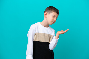 Wall Mural - Little kid boy isolated on blue background holding copyspace with doubts