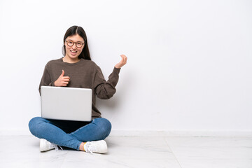 Wall Mural - Young woman with a laptop sitting on the floor making guitar gesture