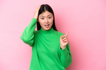 Poster - Young Chinese woman isolated on pink background surprised and pointing finger to the side