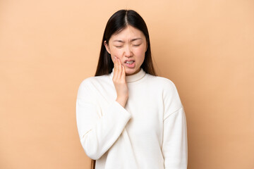 Poster - Young Chinese woman isolated on beige background with toothache