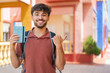 © luismolinero - Young Arabian handsome man holding a passport at outdoors pointing to the side to present a product