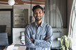 © fizkes - Happy successful attractive Indian business man in casual standing in office with arms crossed, looking at camera with toothy smile, posing for professional portrait with workplace in background