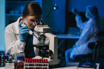 Wall Mural - team of biochemical research scientists working with a microscope for vaccine development in pharmac