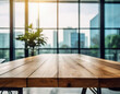 An empty wooden table top with a blurred modern office space background, featuring glass walls and a bright, airy atmosphere, suitable for product display or as a clean, minimalist workspace