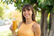 © luismolinero - Young woman holding an orange juice at outdoors smiling a lot