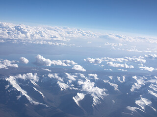 Wall Mural - An aerial view of blue sky, white clouds and snow-capped mountains