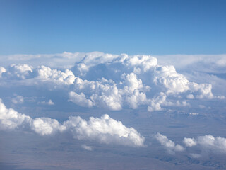 Wall Mural - An aerial view of blue sky, white clouds and snow-capped mountains