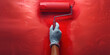 hand painter with painting roller paints wall red paint close up