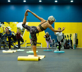 a slender athletic woman in the gym is beautifully engaged in yoga exercises on a mat