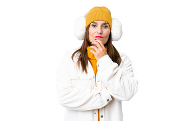 Wall Mural - Middle age woman wearing winter muffs over isolated chroma key background having doubts and with confuse face expression
