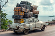 Old car on the road by the sea on a sunny day loaded with many suitcases