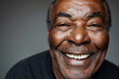 Close-up portrait of an 80-year-old senior man, emanating positivity and vitality with his joyful smile and expressive eyes, against a sleek gray studio backdrop