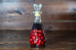 Glass bottle of homemade raspberry liqueur on a wooden background, closeup. Berry alcoholic drinks concept