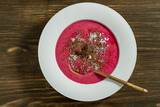 Fototapeta Pomosty - Sweet summer cherry soup in a white plate on a wooden background, closeup, top view. Hungarian cold red cherry soup with yogurt or cream, sprinkled with grated chocolate, powdered sugar and hazelnuts