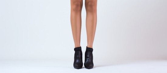 Poster - A womans leg in black boots is depicted on a white background, showcasing a stylish footwear choice that accentuates her entire lower body