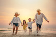 © Garun Studios - brother, children, together, sea, togetherness, parent, beach, having, sunset, childhood. A family is playing in the sea, with the children holding hands and the adults running through the beach.