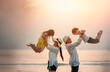© Garun Studios - together, beach, sunrise, silhouette, play, freedom, sea, parent, smile, children. A family is playing in the sea, with two adults holding their children up in the air. Scene is joyful and carefree.