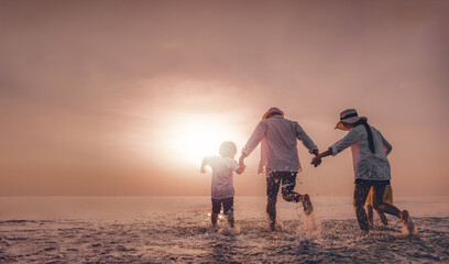 Wall Mural - parent, walking, children, beach, sunset, together, run, sunrise, freedom, childhood. A family of three, a man, a woman and a child, are playing in the beach.