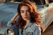 © Formoney - A woman with red hair is posing in front of an old blue car