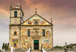 ornately decorated colorful catholic church with tiled facades of religious scenes with dramatic sky 