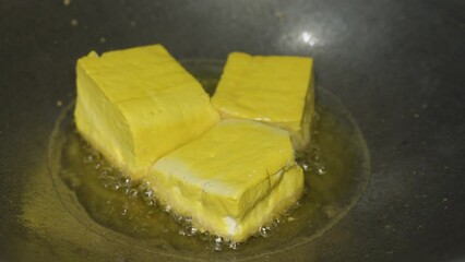 Wall Mural - the process of cooking tofu by frying the tofu until it turns almost golden yellow