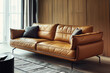 A European light brown leather three seater sofa, with brass legs, straight armrests with a square flat top, and black metal feet. The design is simple yet full of modern elements.