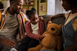 © Marko Geber - African American family spending time together with a teddy bear at home