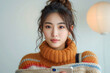 Stylish young lady in a knitted sweater interacting with her mobile phone, online shopping