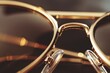 Closeup of designer sunglasses with polarized lenses and gold-plated frames, stacked with a pair of glasses on top